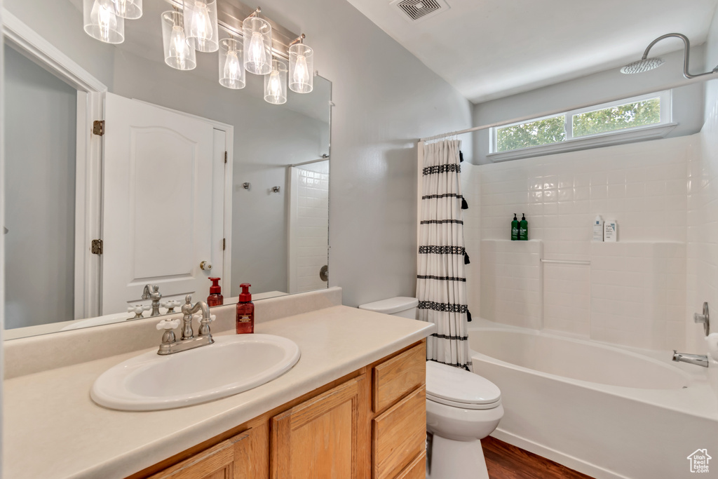 Full bathroom featuring hardwood / wood-style flooring, vanity, shower / tub combo with curtain, and toilet