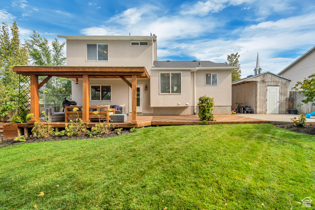 Back of property featuring outdoor lounge area, a yard, a wooden deck, and a storage unit