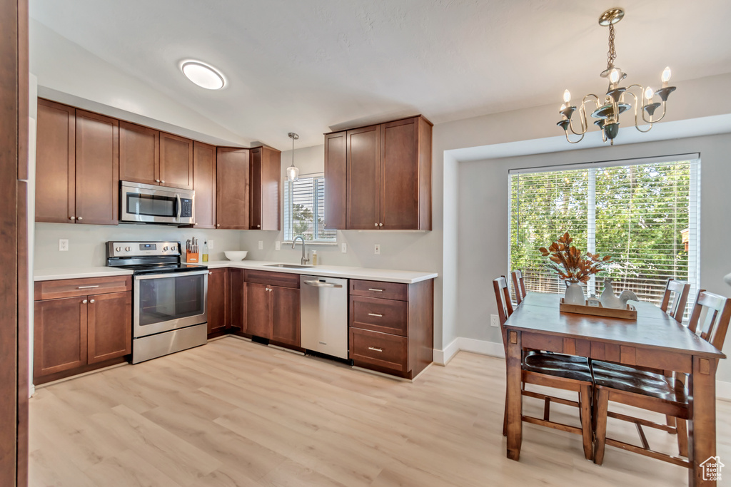 Kitchen with sink, decorative light fixtures, stainless steel appliances, a notable chandelier, and light wood-type flooring