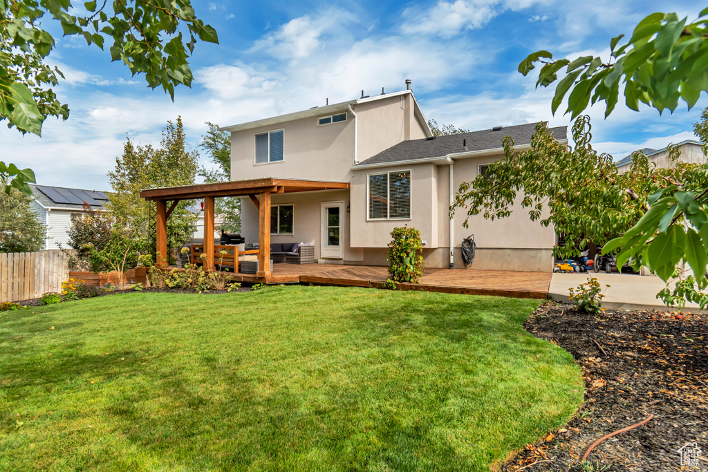 Rear view of property with a wooden deck and a lawn