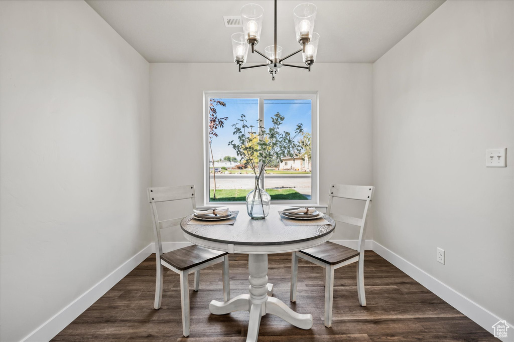 Dining space with dark hardwood / wood-style floors and an inviting chandelier