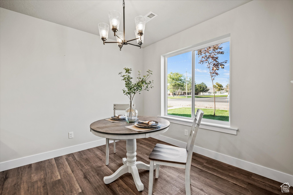 Dining area with a notable chandelier and dark hardwood / wood-style flooring