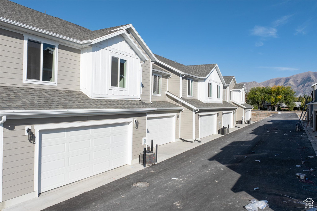 Exterior space with central air condition unit, a garage, and a mountain view
