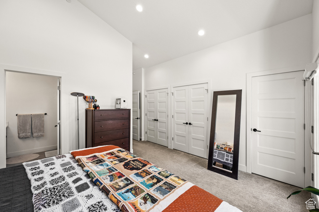 Carpeted bedroom featuring high vaulted ceiling, ensuite bath, and two closets