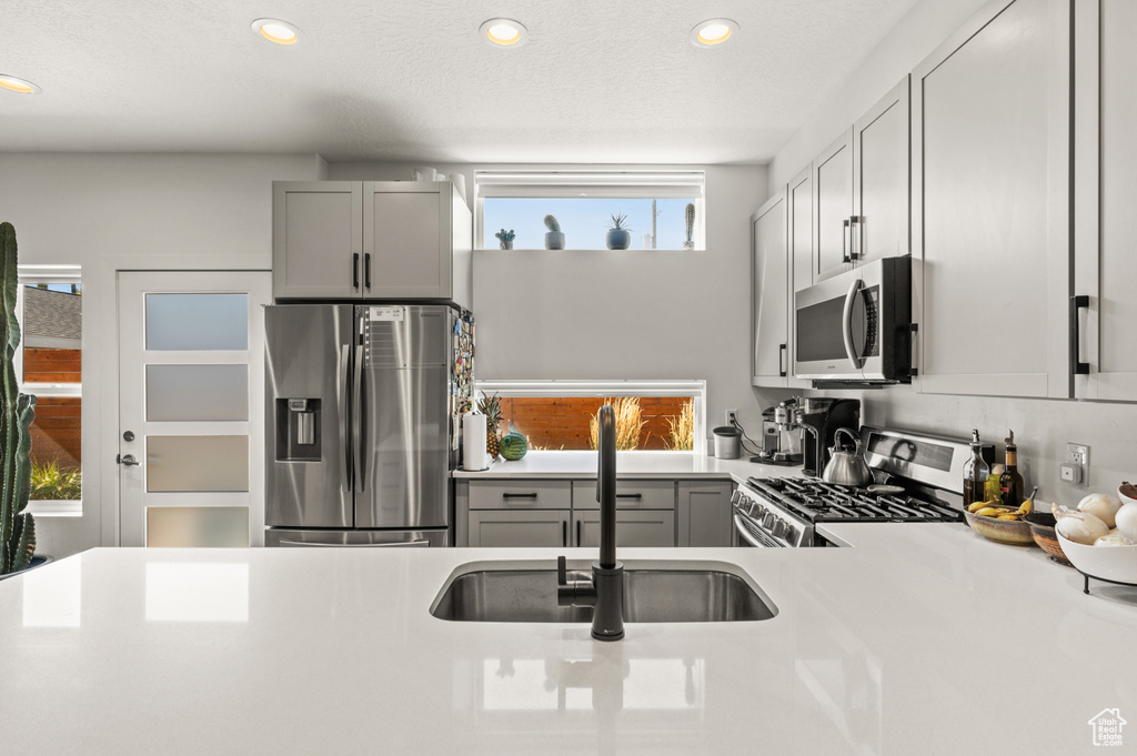 Kitchen with gray cabinets, stainless steel appliances, sink, and a textured ceiling