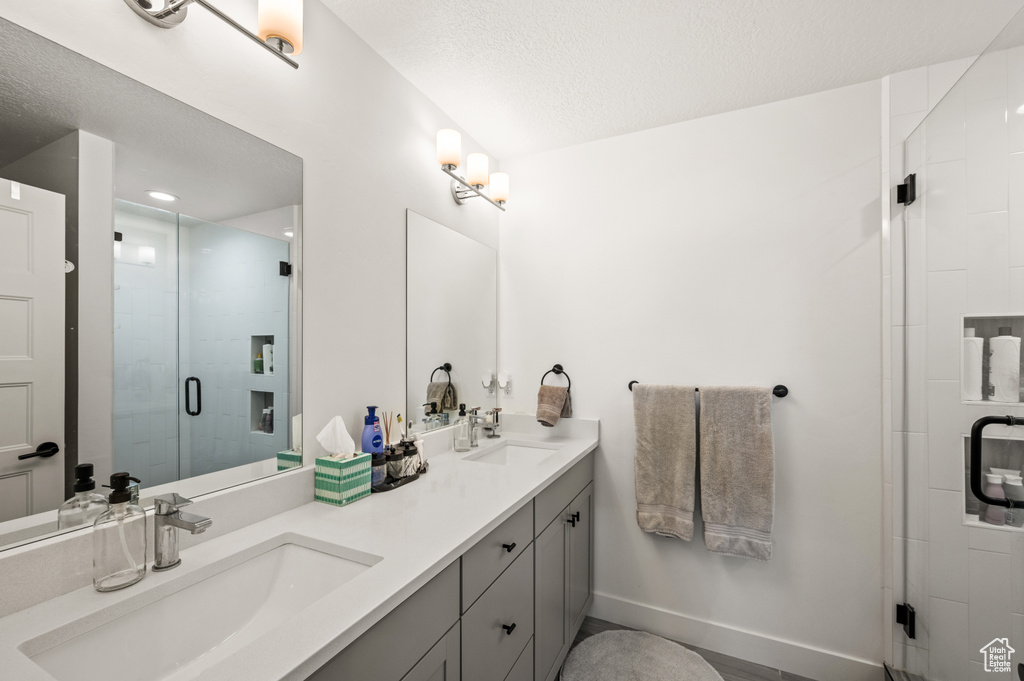 Bathroom with a shower with door, vanity, and a textured ceiling