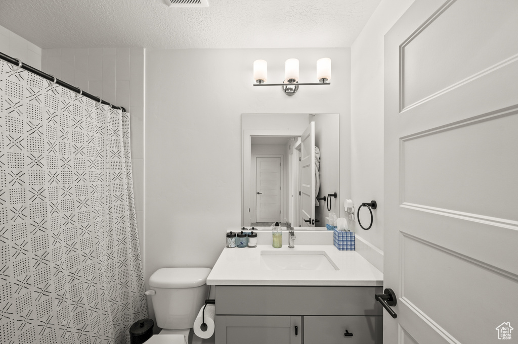 Bathroom with toilet, vanity, and a textured ceiling