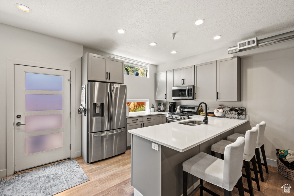 Kitchen with kitchen peninsula, gray cabinets, sink, and stainless steel appliances