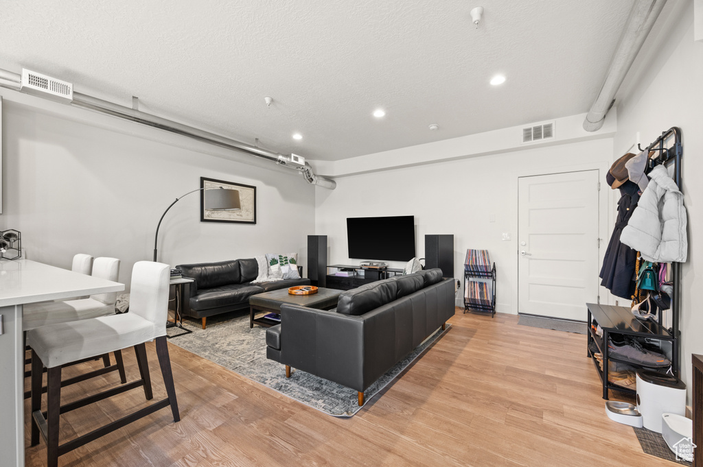 Living room with light wood-type flooring and a textured ceiling