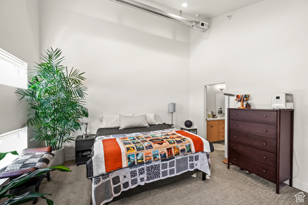 Carpeted bedroom featuring ensuite bathroom and a towering ceiling