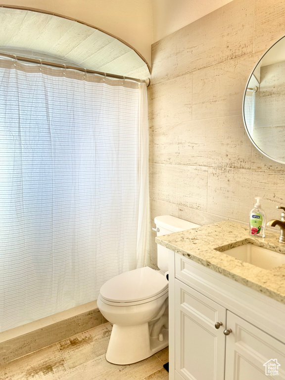 Bathroom with hardwood / wood-style flooring, toilet, walk in shower, and vanity