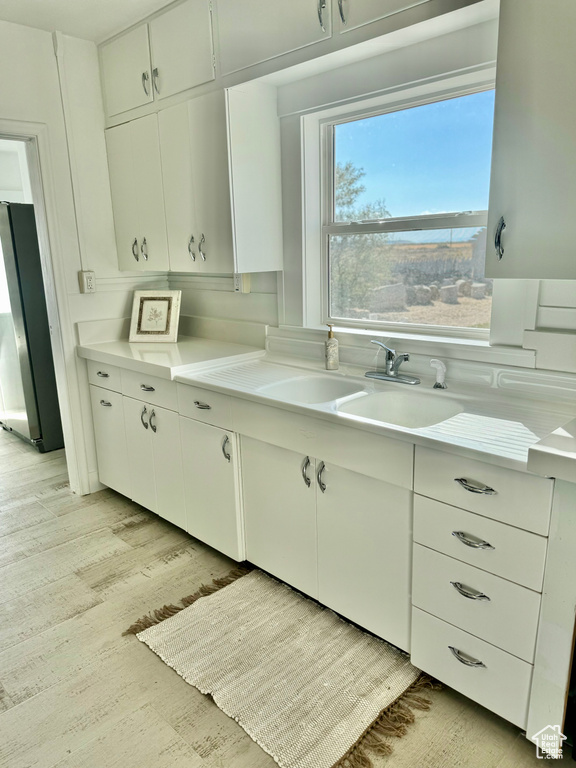 Kitchen with white cabinets, stainless steel refrigerator, and light hardwood / wood-style flooring