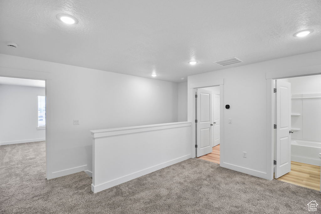 Spare room featuring light carpet and a textured ceiling