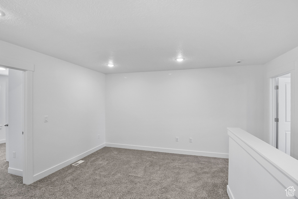 Empty room featuring light carpet and a textured ceiling