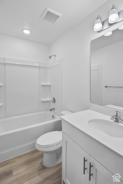 Full bathroom with hardwood / wood-style flooring, tub / shower combination, vanity, and toilet