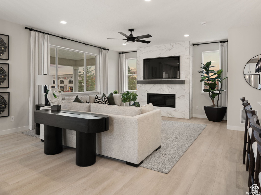 Living room featuring a fireplace, ceiling fan, and light hardwood / wood-style floors