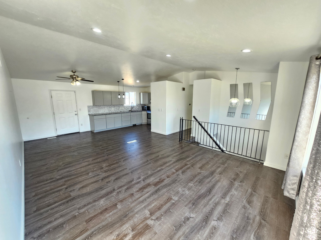 Unfurnished living room featuring ceiling fan, sink, and dark hardwood / wood-style floors