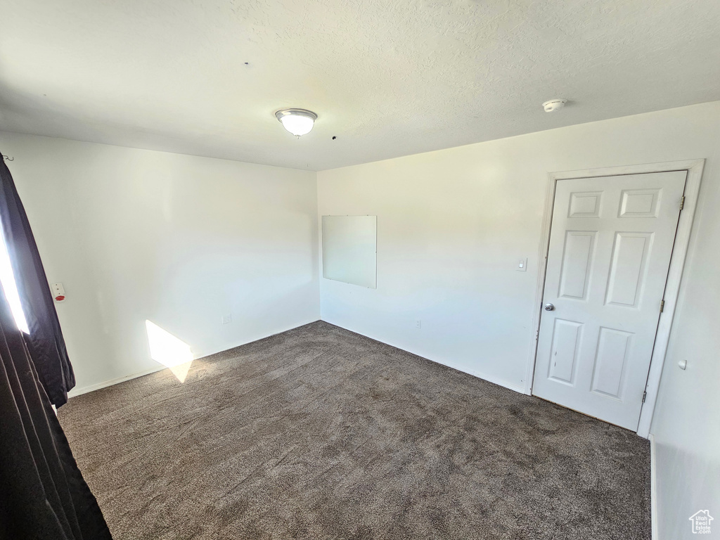 Unfurnished room with dark carpet and a textured ceiling