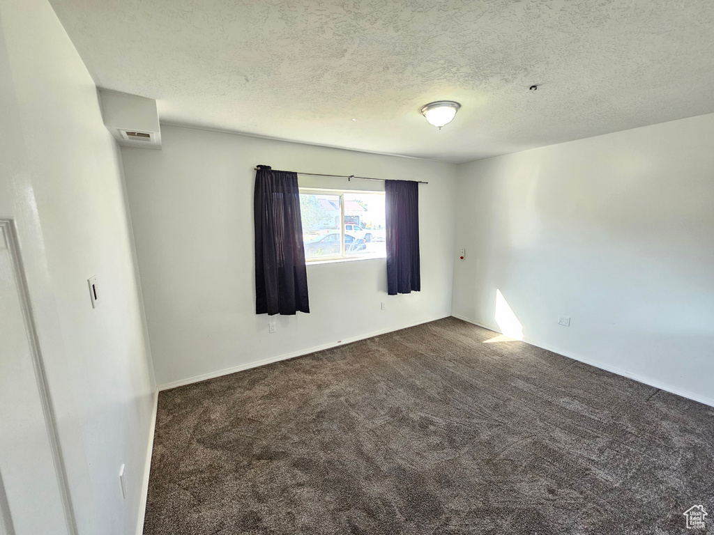 Carpeted empty room with a textured ceiling