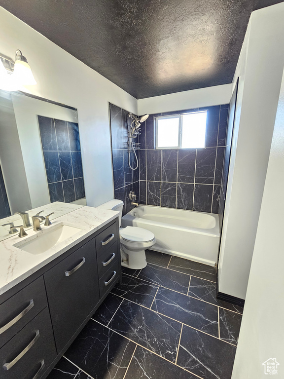 Full bathroom with vanity, toilet, tiled shower / bath, and a textured ceiling