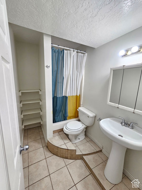 Bathroom with a shower with curtain, tile patterned floors, a textured ceiling, and toilet