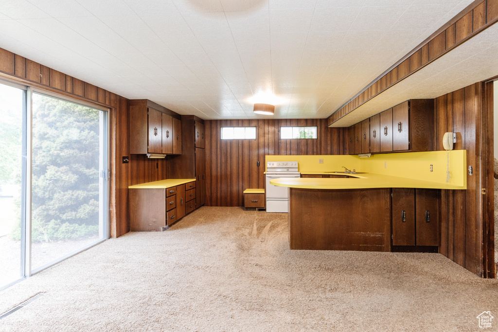 Kitchen featuring kitchen peninsula, white stove, and wooden walls