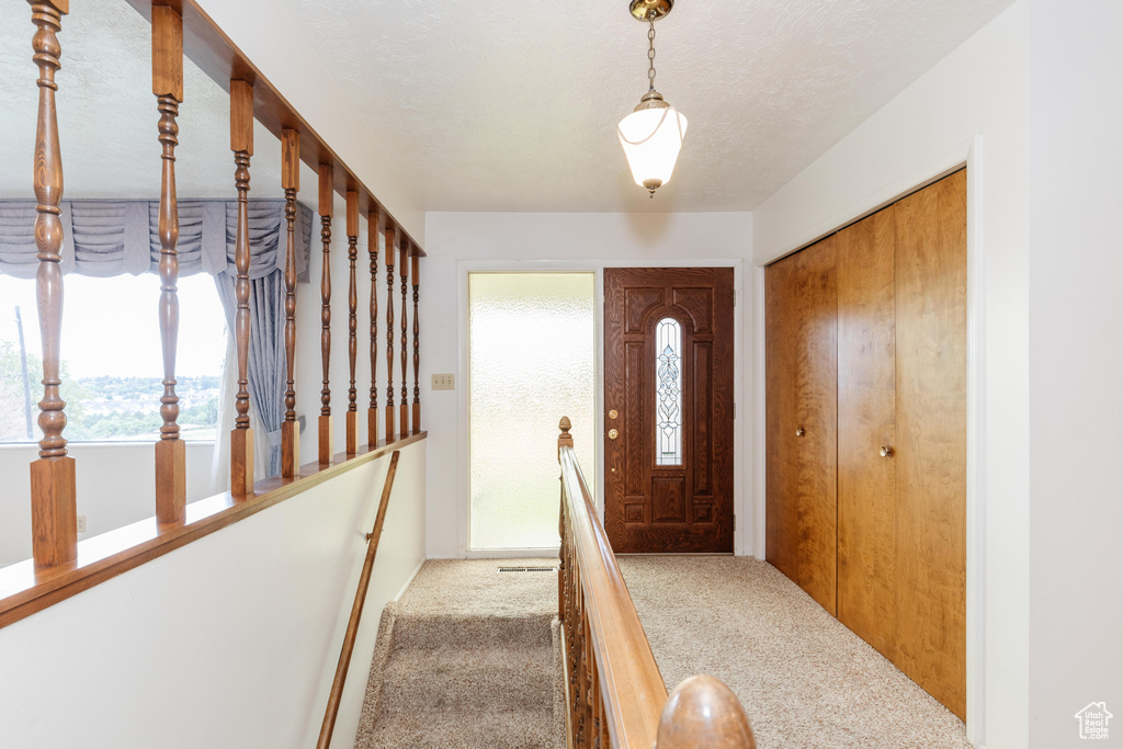 Carpeted entrance foyer featuring a textured ceiling