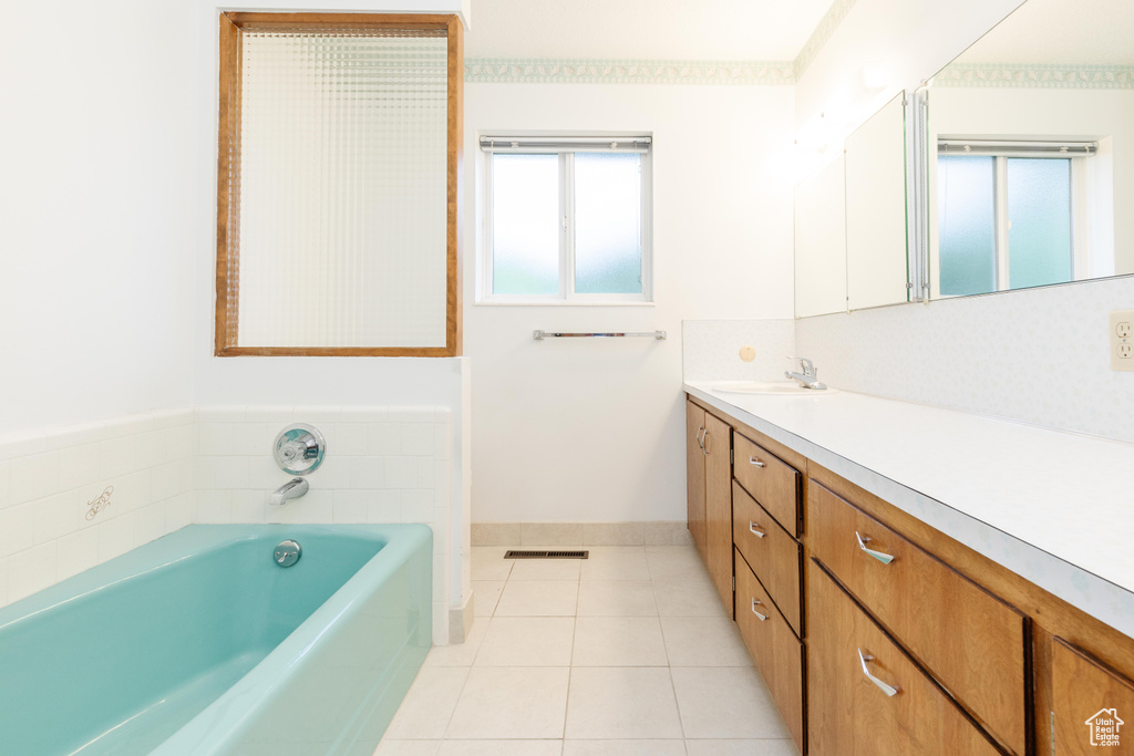 Bathroom with tile patterned flooring, a washtub, and vanity