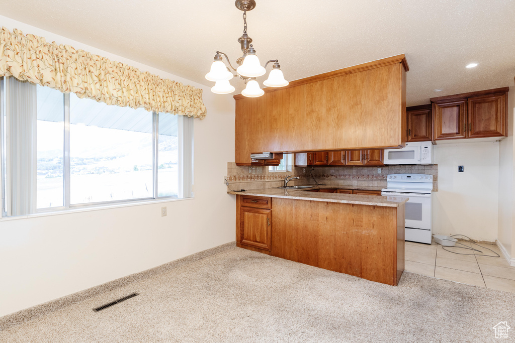 Kitchen with kitchen peninsula, white appliances, light carpet, and tasteful backsplash