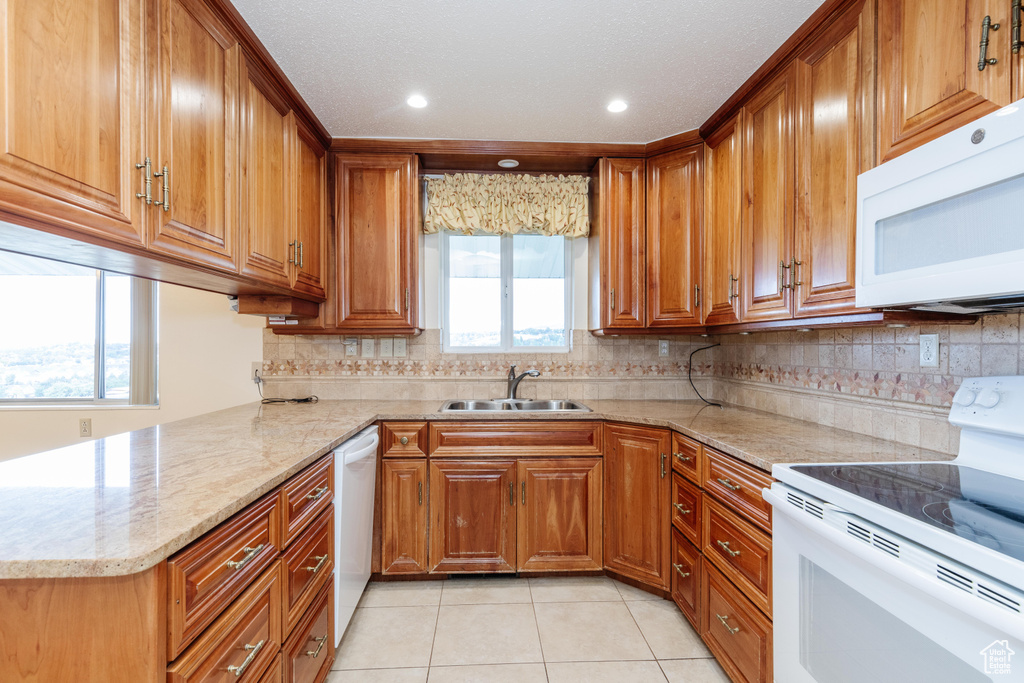 Kitchen featuring a wealth of natural light, white appliances, sink, and kitchen peninsula