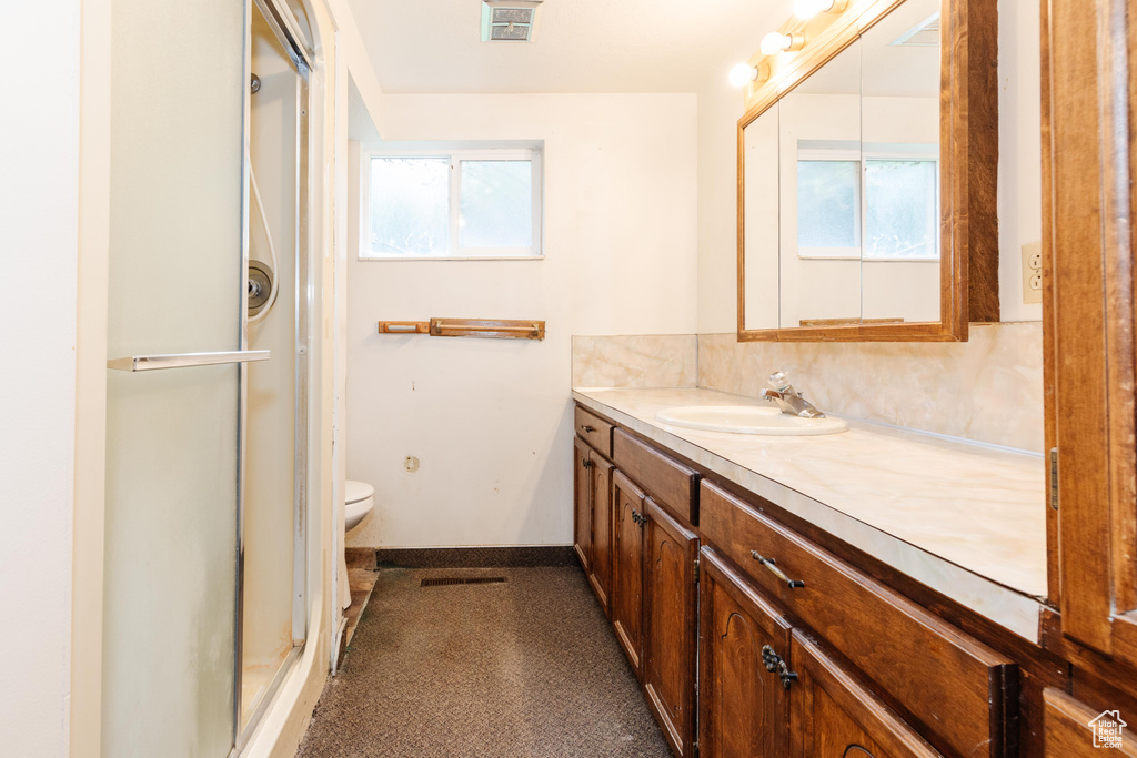 Bathroom with a shower with shower door, vanity, and toilet