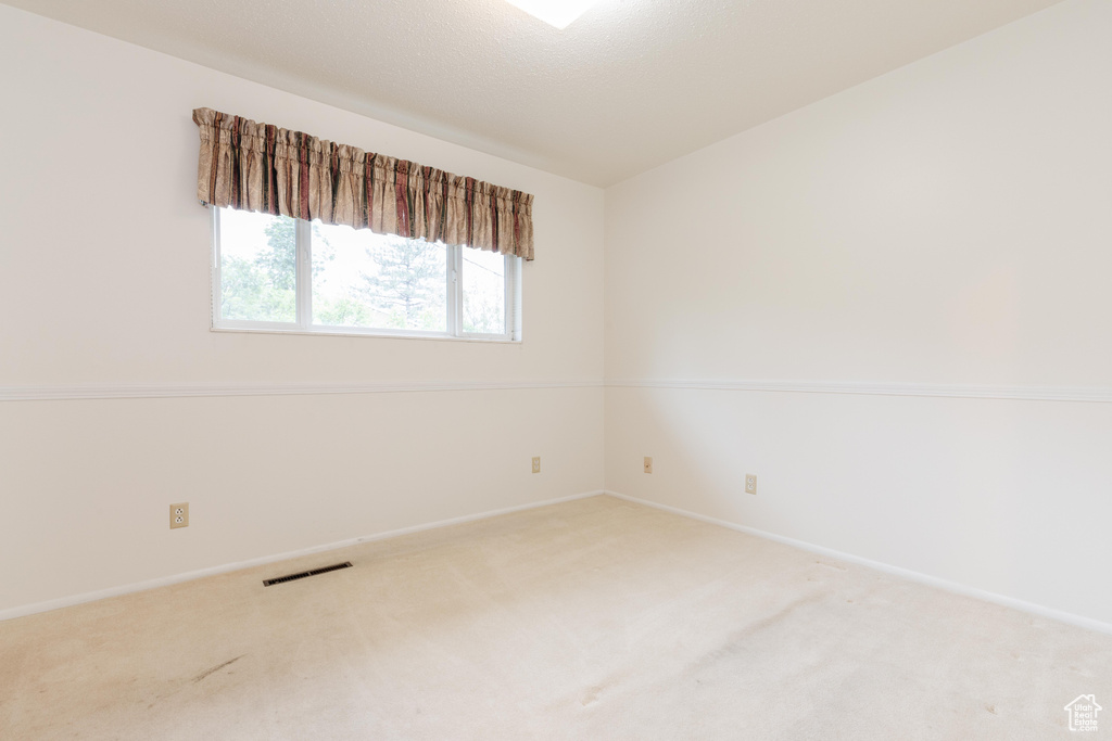 Spare room featuring vaulted ceiling and carpet flooring