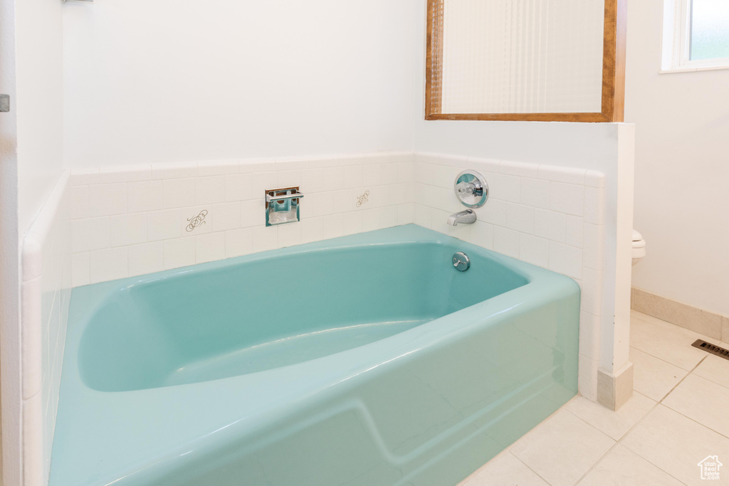 Bathroom with tile patterned flooring, toilet, and a bath