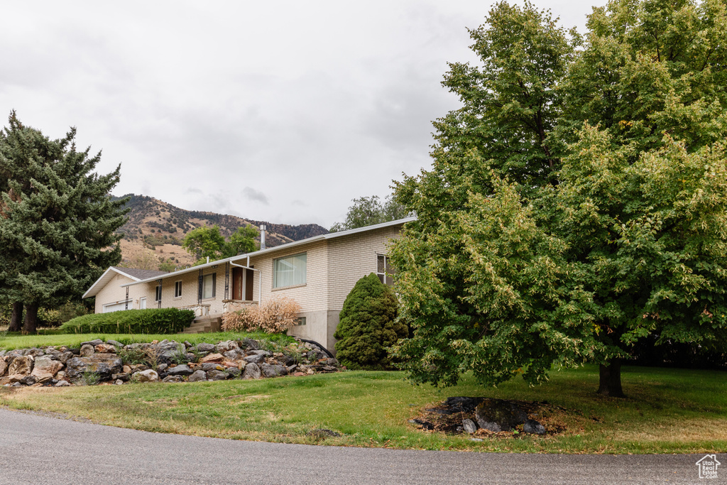 View of property exterior with a yard and a mountain view