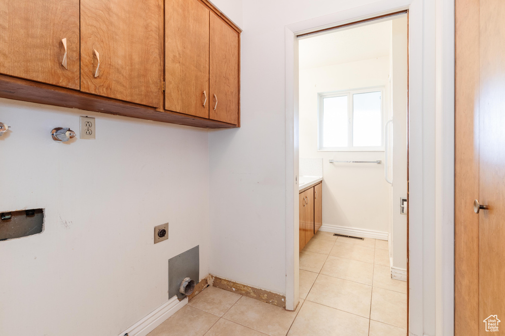 Laundry area featuring cabinets, hookup for an electric dryer, and light tile patterned flooring