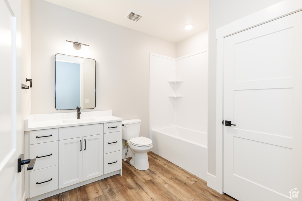 Full bathroom featuring hardwood / wood-style floors, tub / shower combination, vanity, and toilet