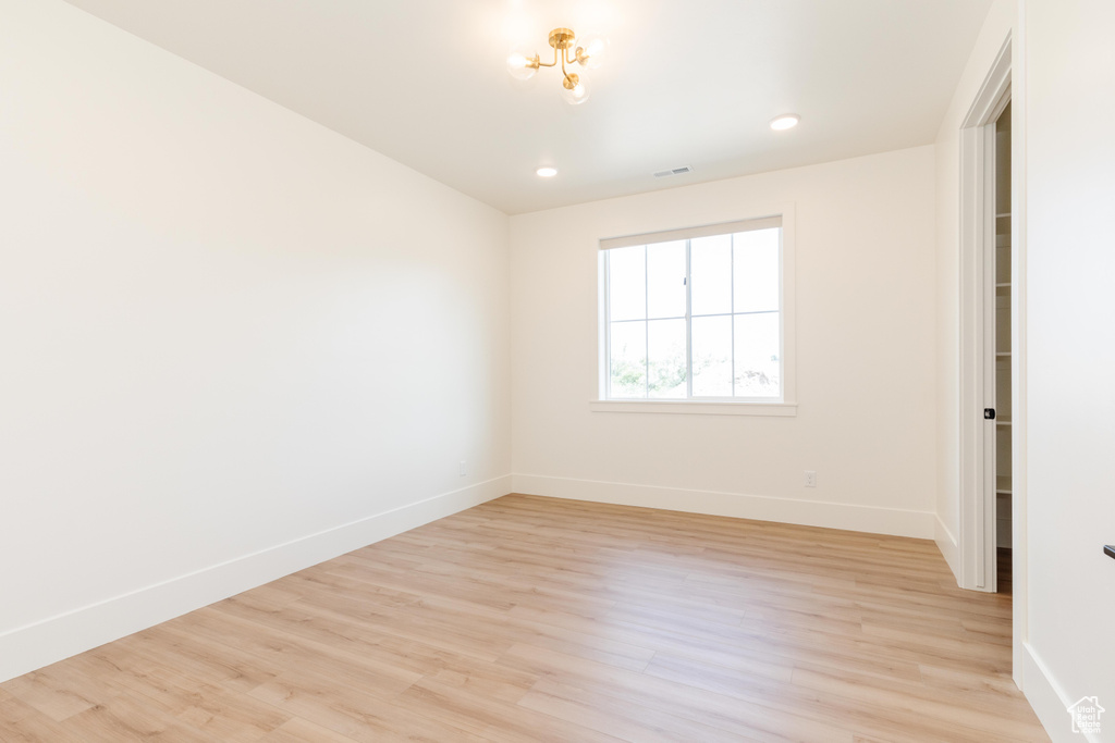 Empty room with an inviting chandelier and light hardwood / wood-style flooring