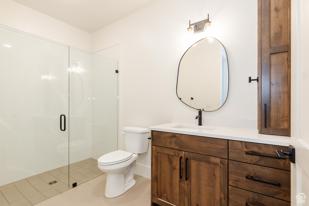 Bathroom featuring vanity, toilet, and a shower with door