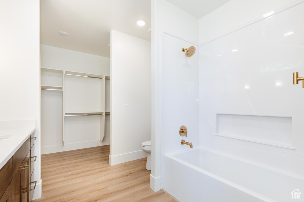 Full bathroom featuring hardwood / wood-style floors, vanity, shower / tub combination, and toilet