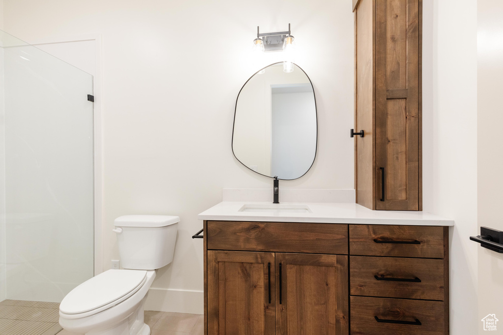 Bathroom with walk in shower, tile patterned floors, vanity, and toilet