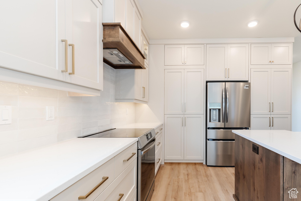 Kitchen featuring light hardwood / wood-style floors, white cabinets, and appliances with stainless steel finishes