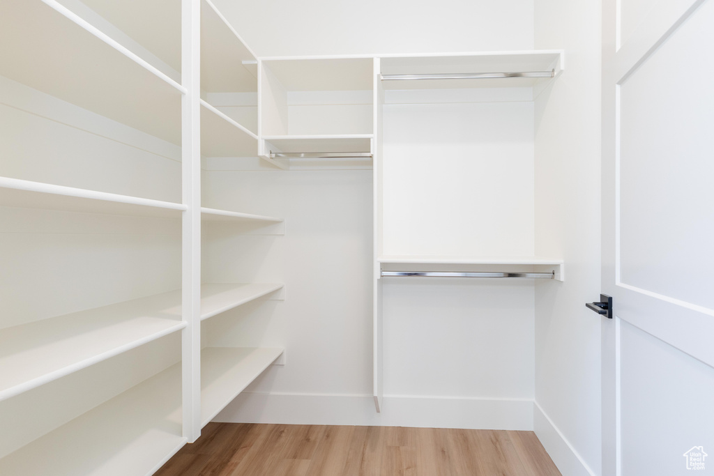 Walk in closet with hardwood / wood-style flooring