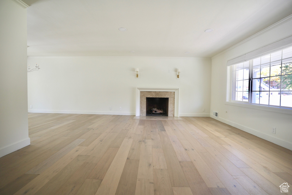 Unfurnished living room featuring ornamental molding and light hardwood / wood-style floors