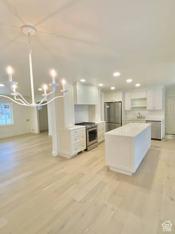 Kitchen with stainless steel appliances, sink, light hardwood / wood-style flooring, and white cabinetry