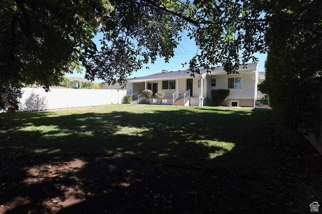 Rear view of property with a yard