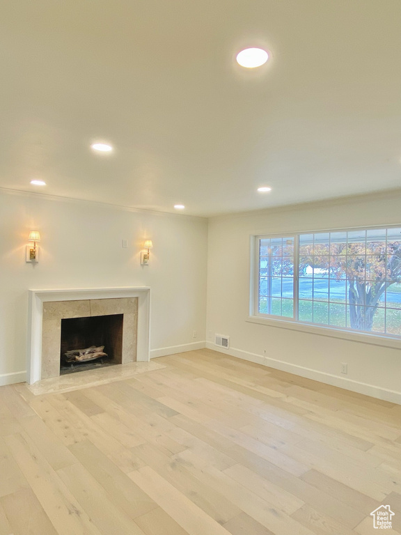 Unfurnished living room with light wood-type flooring and a wealth of natural light