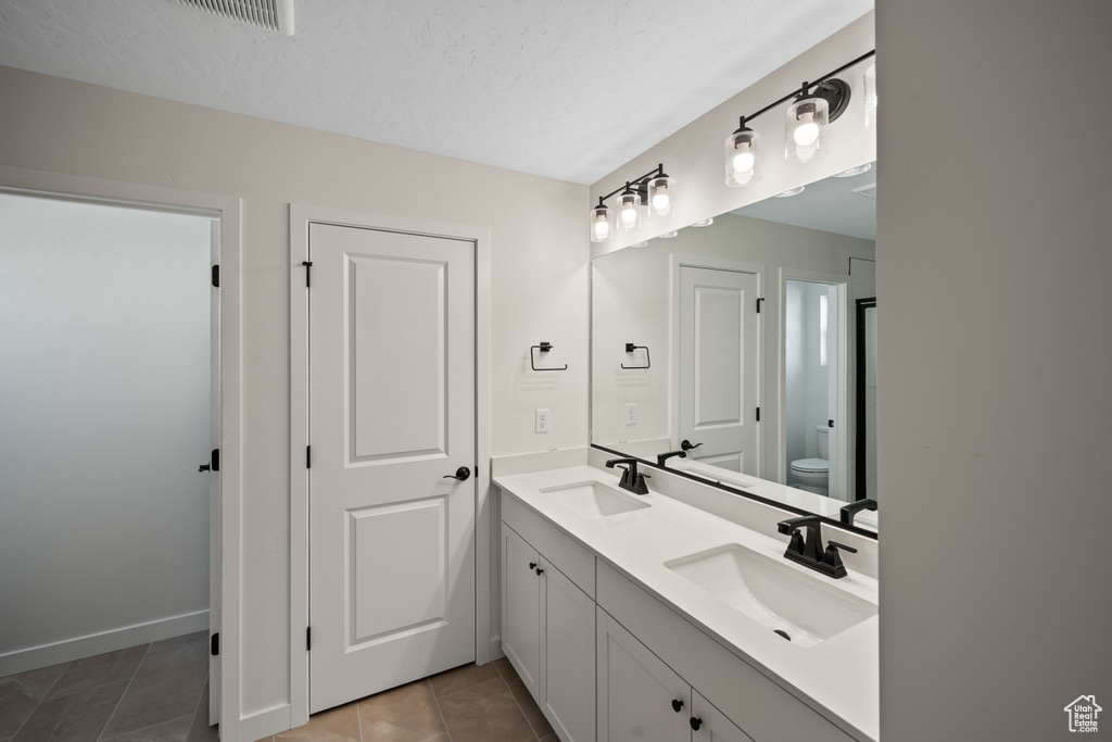 Bathroom with vanity, toilet, and tile patterned floors