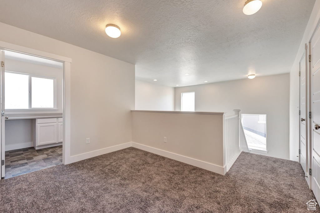 Spare room with a textured ceiling and dark colored carpet