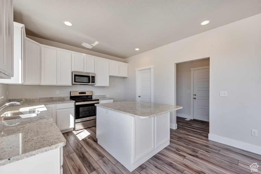 Kitchen featuring white cabinets, appliances with stainless steel finishes, light hardwood / wood-style flooring, and a center island