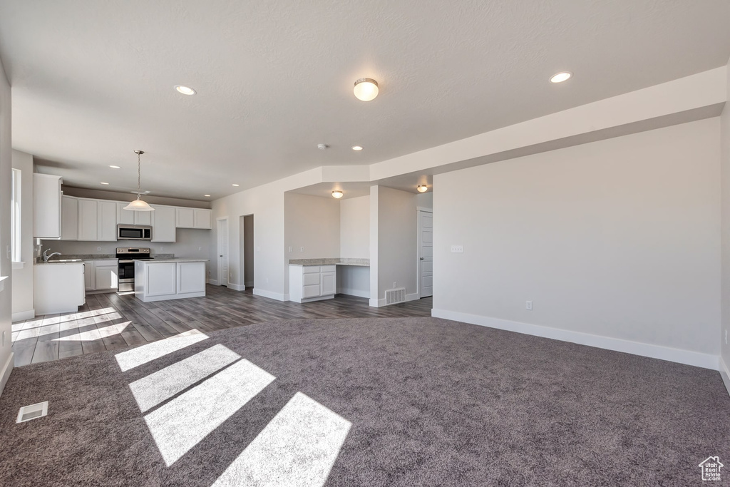 Unfurnished living room featuring dark carpet